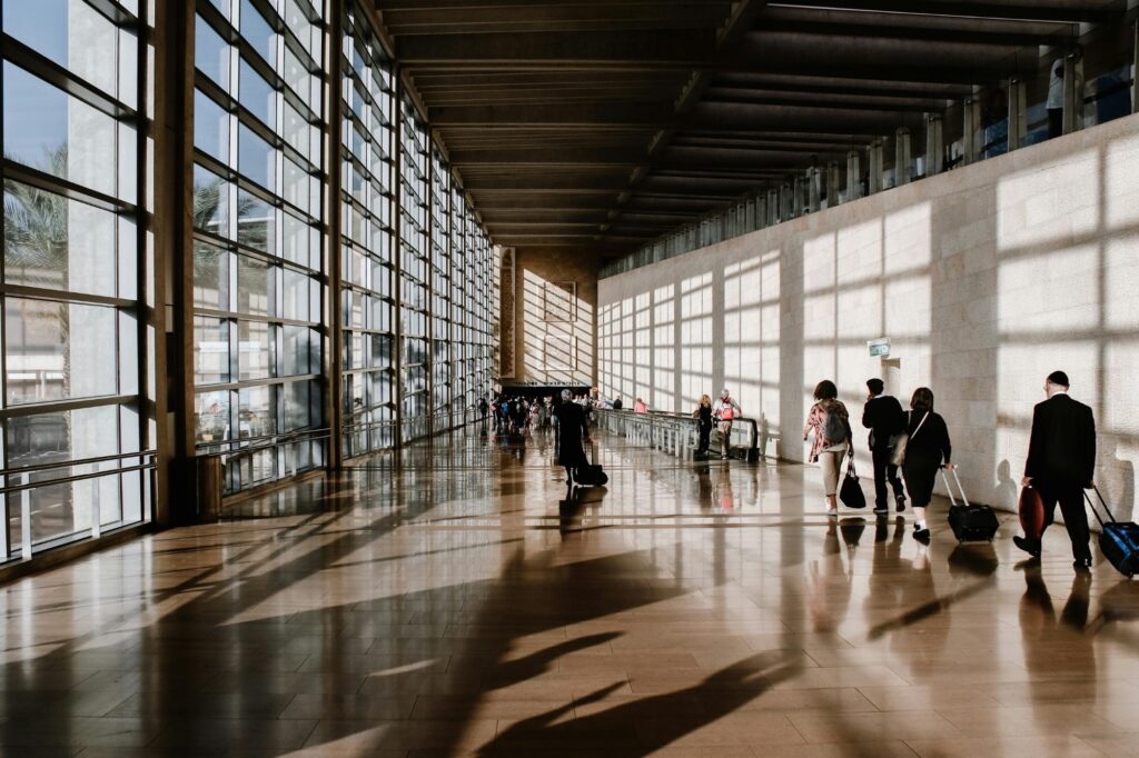 Travelers with luggage walking through a modern airport terminal bathed in natural light