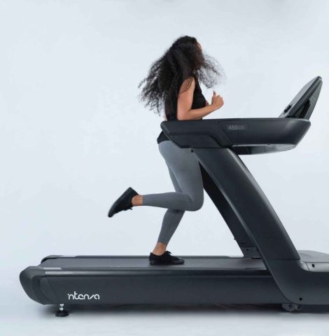 Woman running on an Intenza 450 i2S treadmill against a clean studio background.