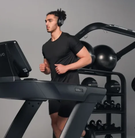 Man running on Intenza 550 e2 treadmill in modern gym with functional training equipment in background